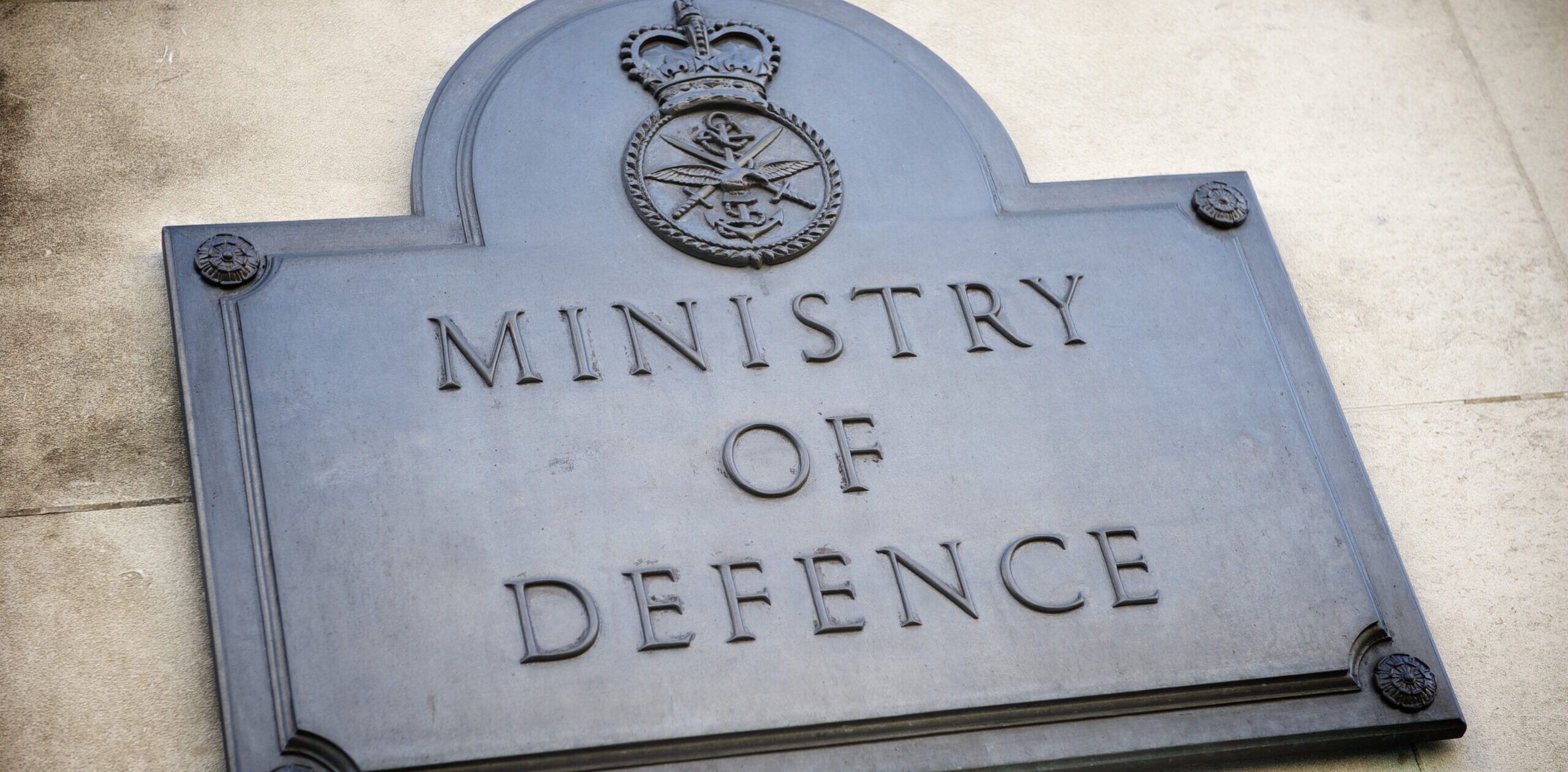 Ministry of Defence Plaque Sign London UK A man with a UAV control panel in his hands, a drone flying above the tank in the background in nature. help of reconnaissance drones in modern warfare.
